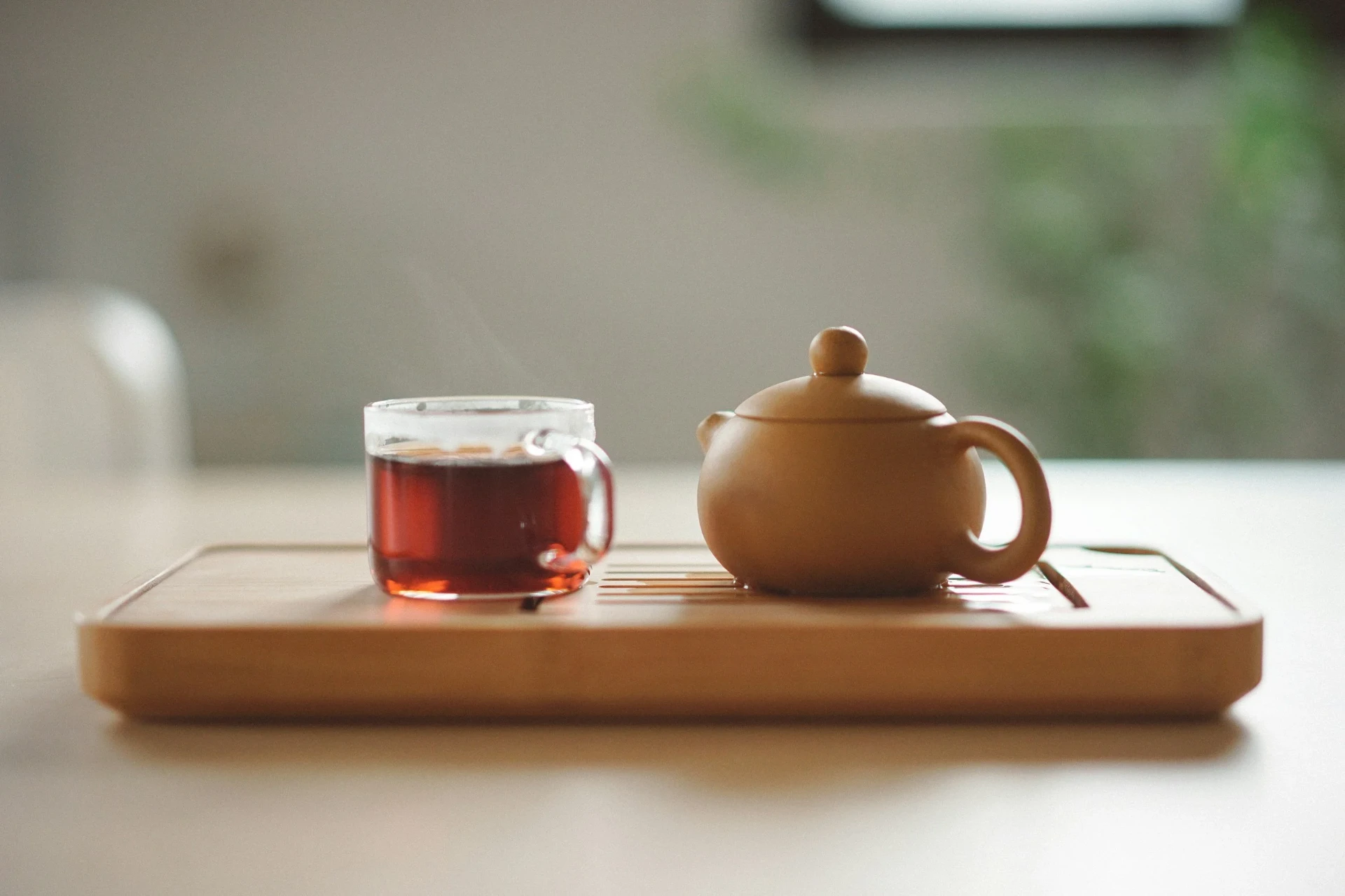 A pot of tea and a cup of tea on a wooden tray