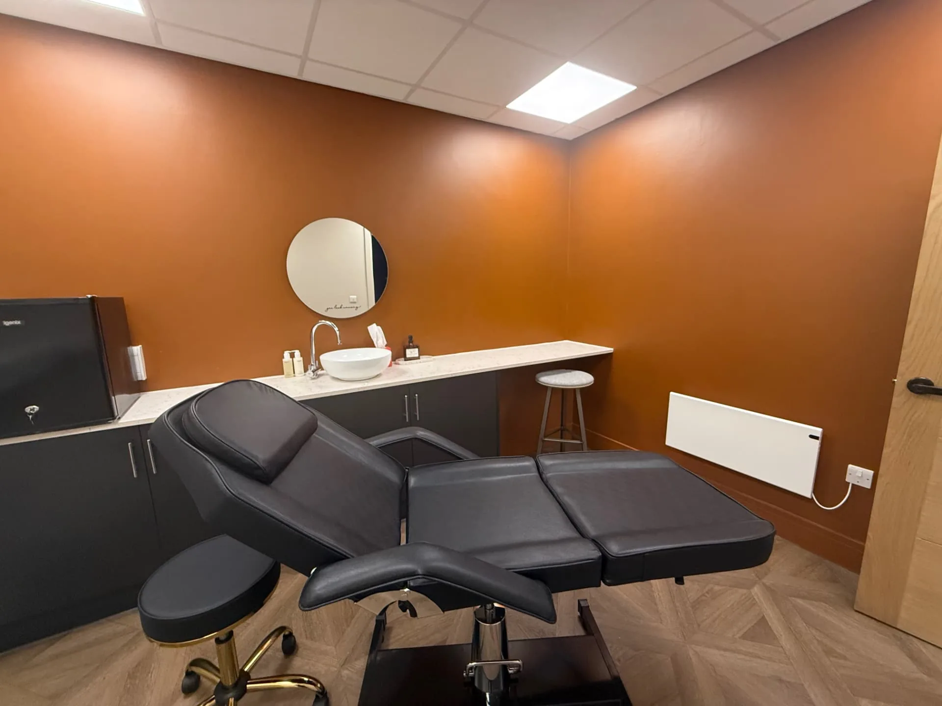 The Beech Room at The Wellness Lounge Leeds with a white treatment couch, round mirror, basin and pendant lights